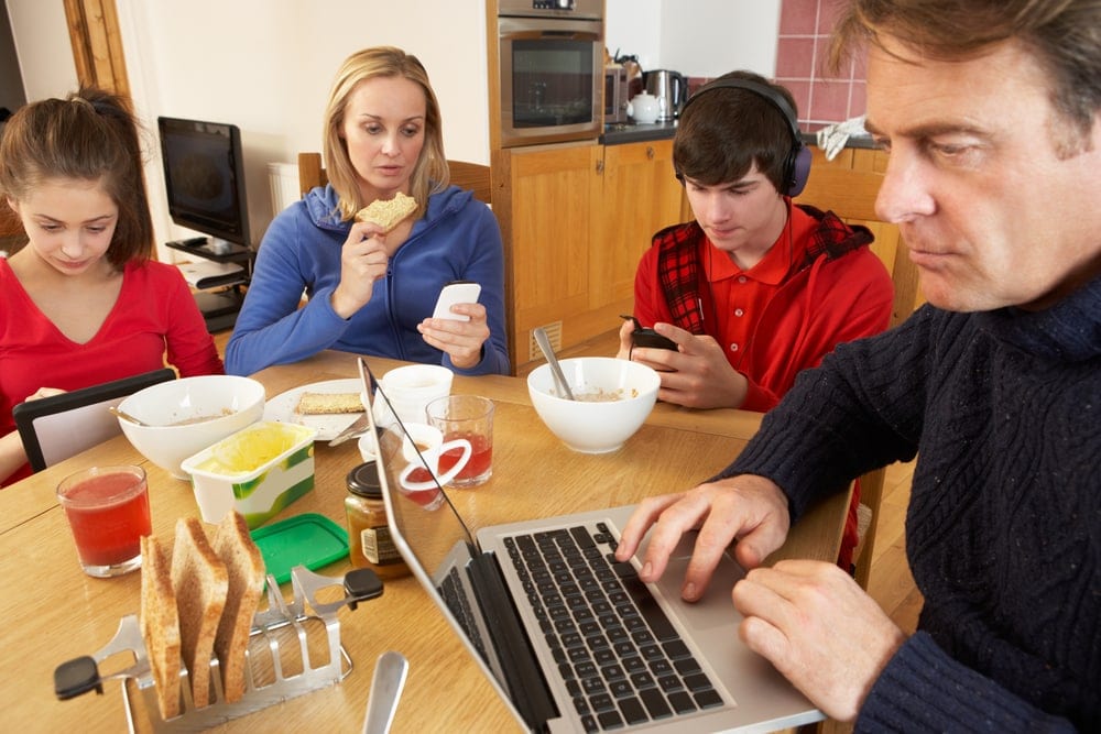 family eats breakfast, looking at screens, not at each other, distracted parenting