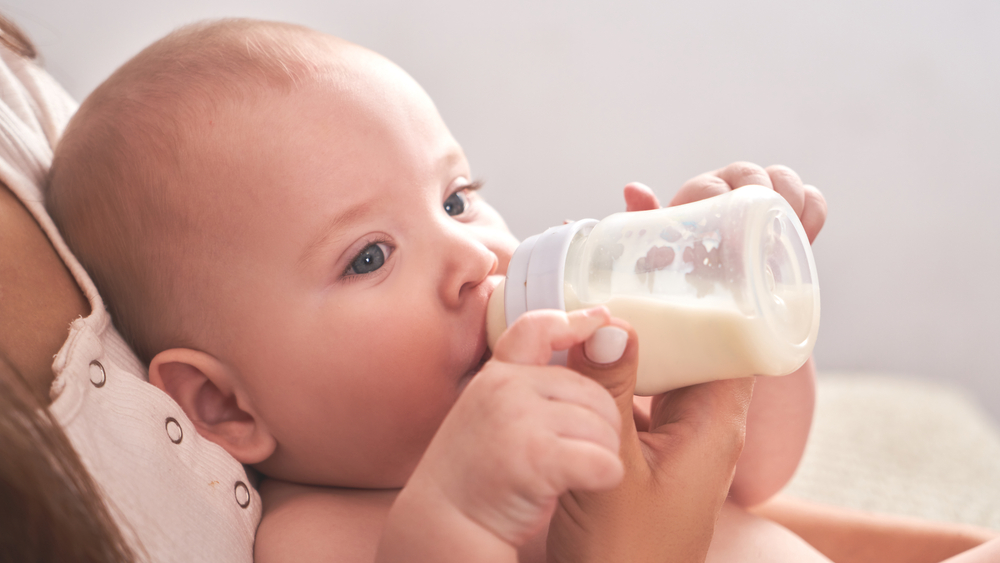 mom gives bottle to hungry baby