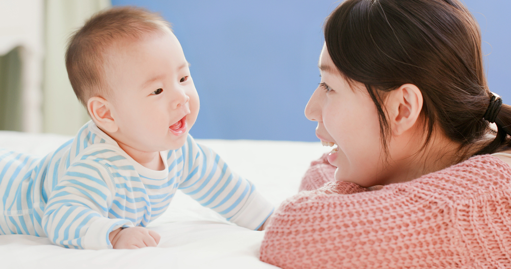 smiling asian baby, small statistician and linguist, reads mother's mouth, learns language