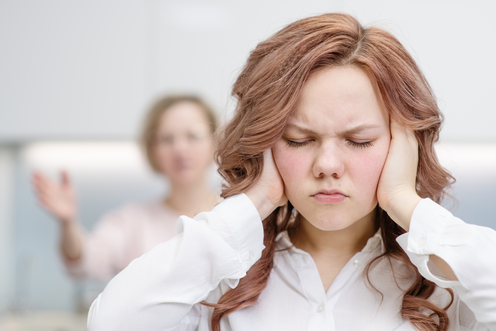 Teen girl covers ears not to hear mother