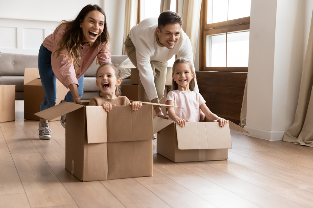 two parents playfully push children in cartons