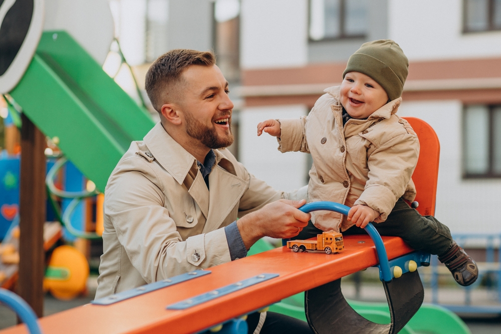 fathers, smiling father, toddler son on seesaw