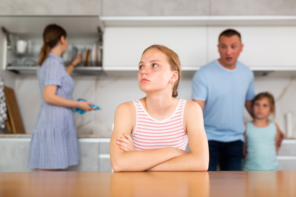 Upset,Teenage,Girl,Sitting,At,Table,In,Home,Kitchen,Frowning