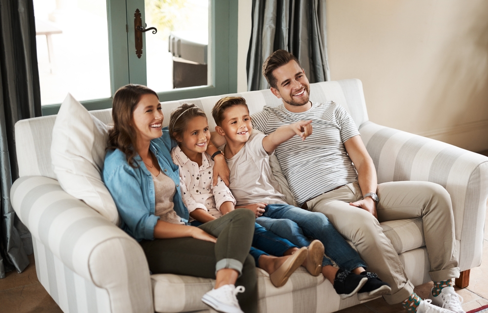 smiling parents children watch tv boy points to screen