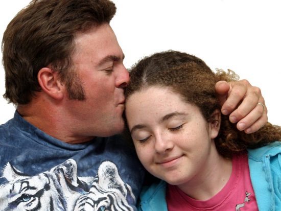 beatific teen daughter, dad as good parent receives kiss