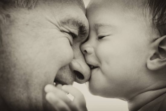 laughing toddler playfully nips laughing grandfather's nose. "Better grandparents"