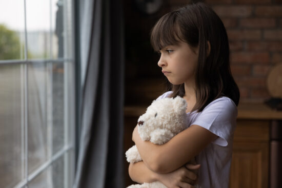 Close,Up,Lonely,Little, campsick Girl,Hugging,Toy,,Looking,Out,Window,