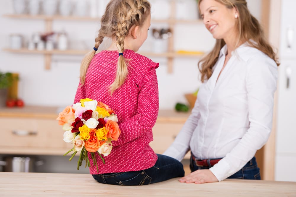 Girl with bouquet for mom behind her back