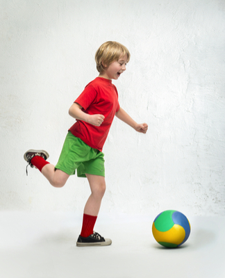 smiling blond boy with visual processing disorder (VPD) plays soccer in red shirt, green shirt