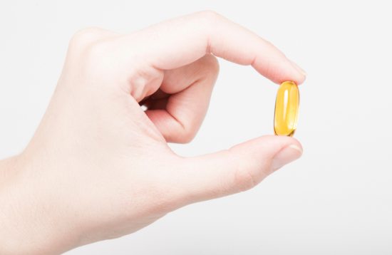 female hand holding vitamin d capsule