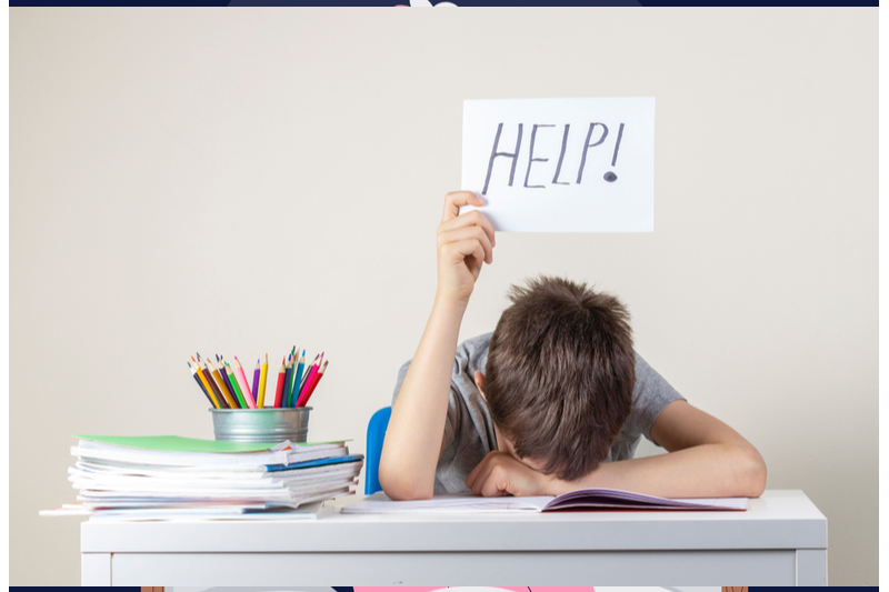 boy falling asleep at homework holding sign help