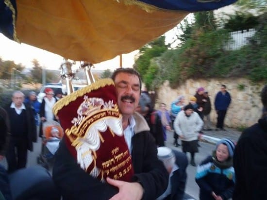 At a celebration, dancing with a Torah scroll.