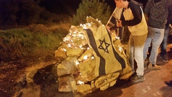 A student leaves a candle at the site of the murder of Rav Yaakov Don.