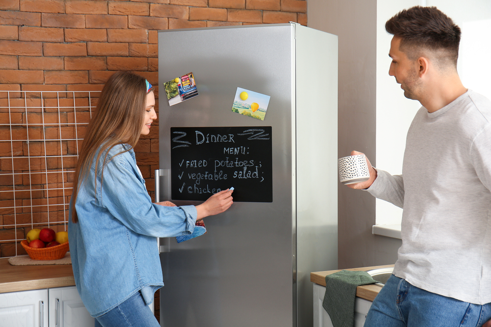 Young,Woman,Writing,Menu,On,Chalkboard,In,Kitchen