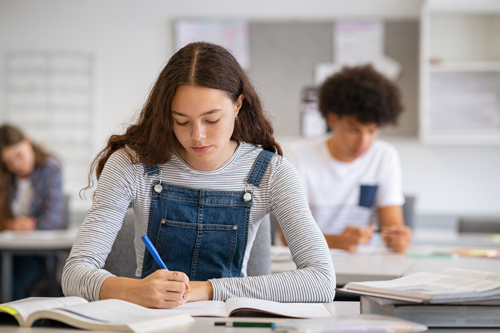 High,School,Student,Taking,Notes,From,Book,For,Her,Study.