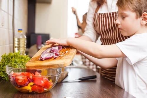 boy cutting veggies with mom