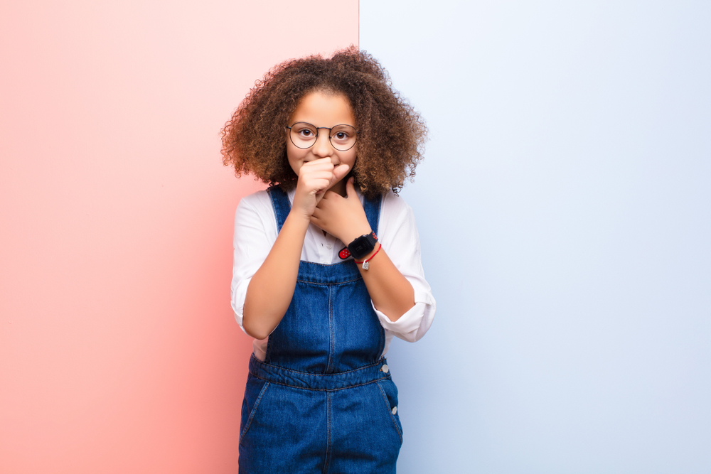 smiling girl covers mouth while coughing, manners