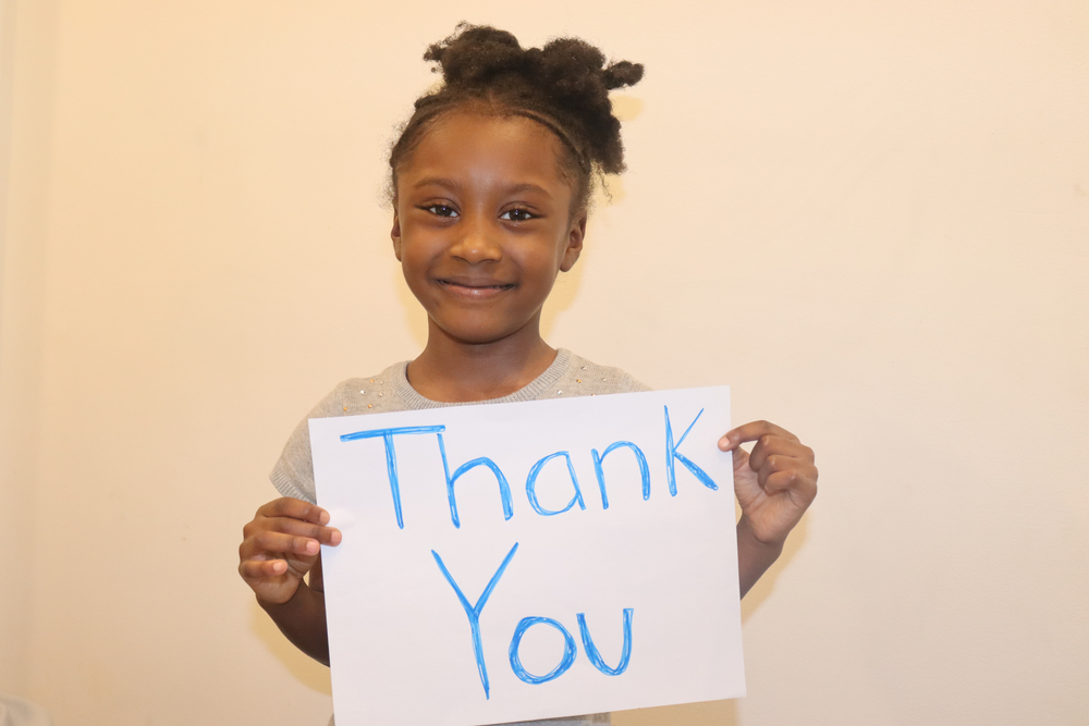 girl holds thank you sign