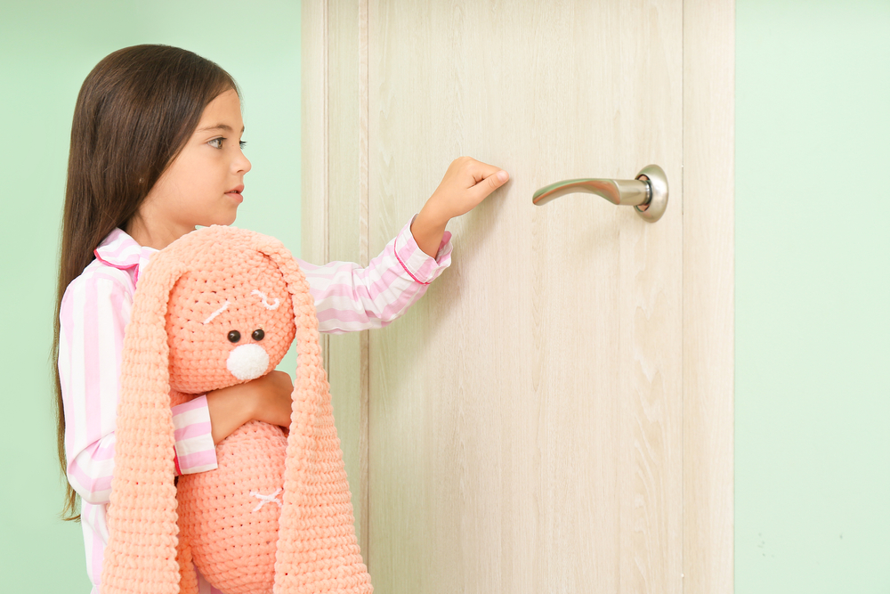 girl in pjs with stuffed animal knocks on door