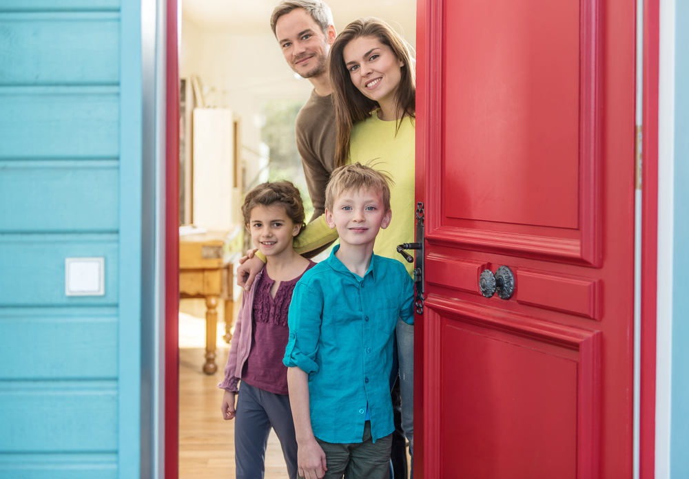 family of four at open door, greet guest