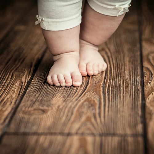 A baby's fat little feet on a wooden floor