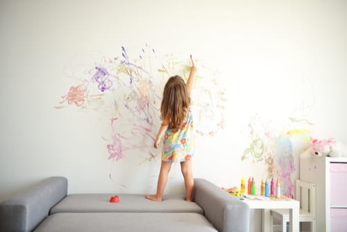 Toddler girl paints the wall of her bedroom