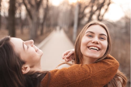 Two teenage girls show joy in each others' company.