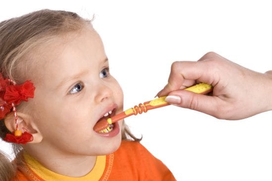 Mother brushes little girl's teeth