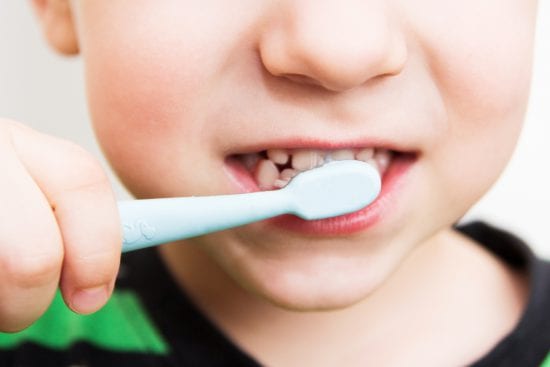 How should kids brush their teeth? Boy brushes teeth