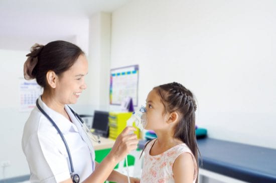 School nurse helps child with asthma inhaler