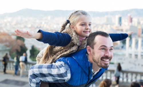 daughter rides father's shoulders as they tour their toqn