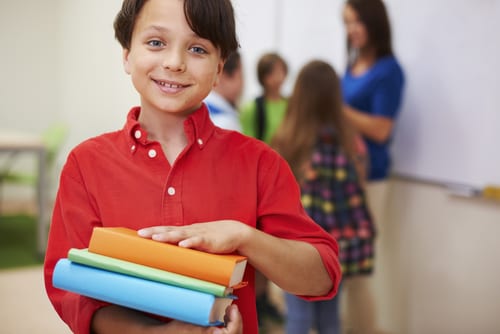 Boy happy to be holding a stack of books