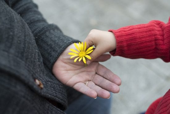 child hands elderly woman a daisy