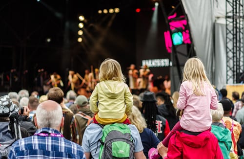 children on parents' shoulders at concert