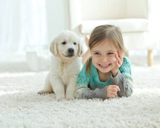 little girl huddles with dog on white rug
