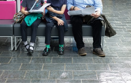 Two kids and a dad (from waist down) in ER waiting room