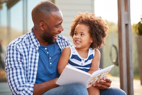 Black Father getting silly as he Reads to Daughter