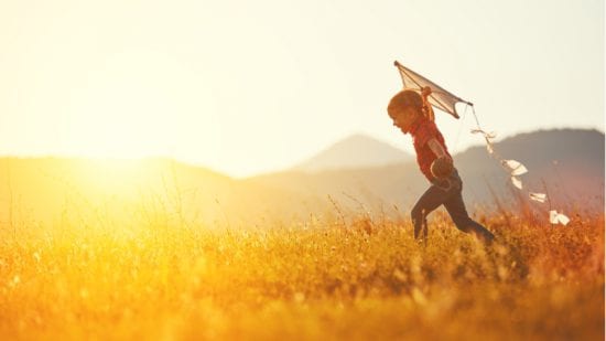 Boy runs with kite outside