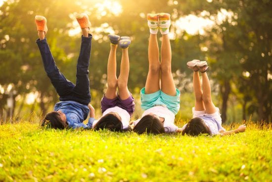 Kids on their backs, legs up, outside in the backyard