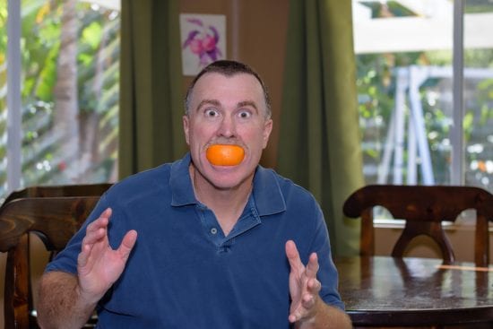 Man getting silly with orange wedge smile