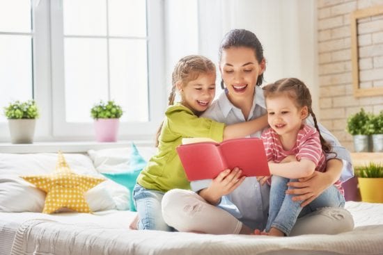 Mother reads to two laughing girls