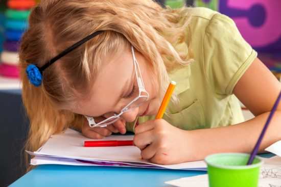 Child victim of the myopia epidemic, wearing glasses while doing close work