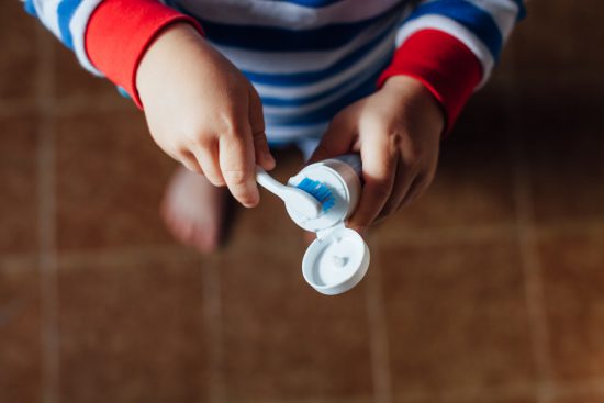 Little boy squeezes toothpaste onto brush