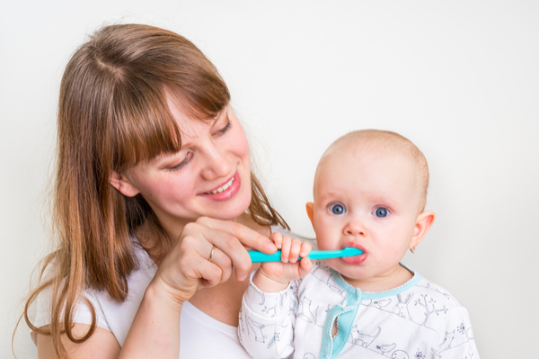 mother brushes baby's teeth