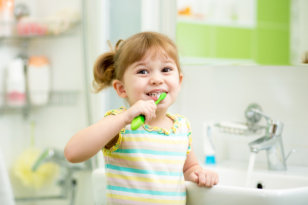 smiling blond girl brushes teeth