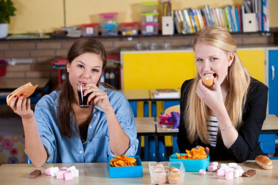 Two Schoolgirls eat junk food and drink soda 