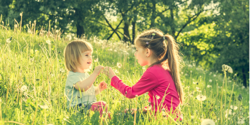 sisters playing in field in morning sun