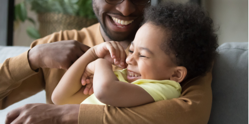 A black father is tickling his son