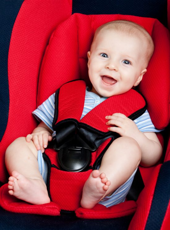 Happy baby in red car seat with black trimmings