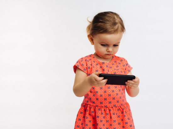 Cute little girl concentrates on phone screen